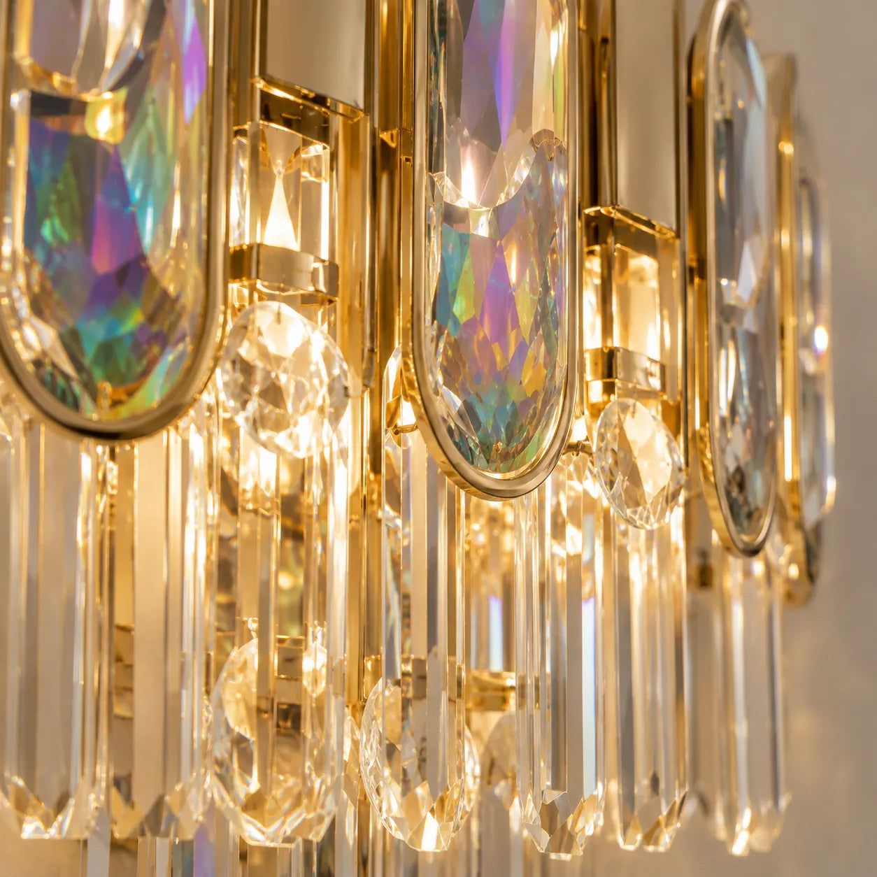 Gros plan sur les reflets irisés du cristal de l'applique murale dorée
